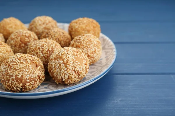 Delicious sesame balls on blue wooden table, closeup. Space for text