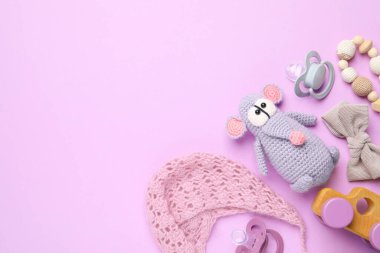 Flat lay composition with pacifiers and other baby stuff on violet background. Space for text
