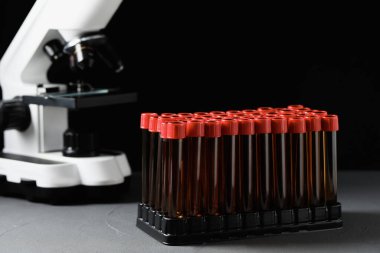Test tubes with brown liquid in stand on grey table against black background