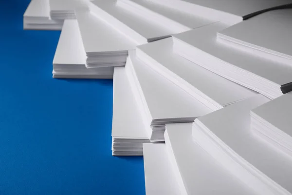 Many stacks of paper sheets on blue background, closeup