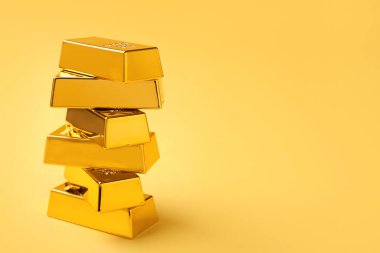 Stack of shiny gold bars on yellow background. Space for text