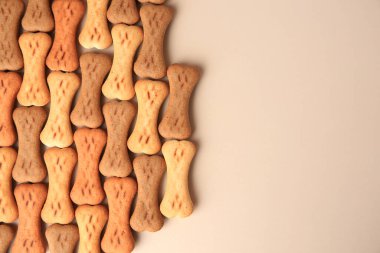 Bone shaped dog cookies on beige background, flat lay. Space for text