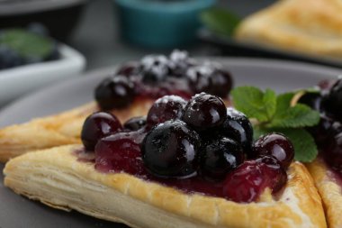 Fresh tasty puff pastry with sugar powder, jam, sweet berries and mint, closeup