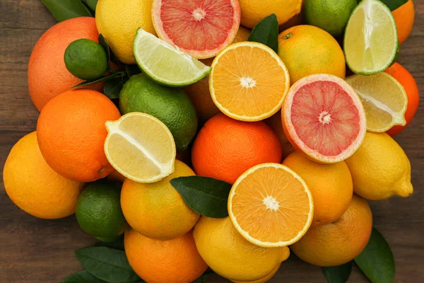 木製のテーブルの上に緑の葉を持つ異なる柑橘類 フラットレイアウト — ストック写真