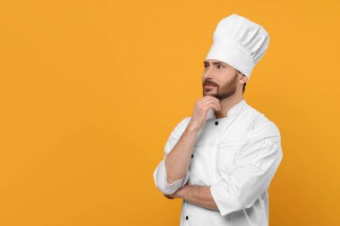 Thoughtful mature chef on orange background, space for text
