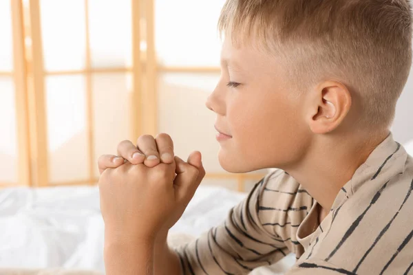 Boy with clasped hands praying at home