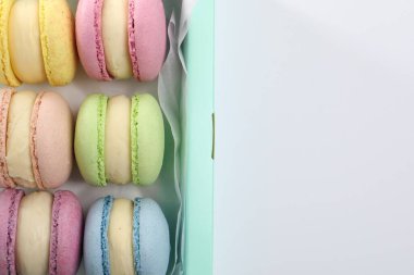 Beyaz arka planda, kutuda bir sürü renkli badem kurabiyesi var.