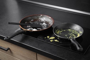 Dirty frying pans on cooktop in kitchen