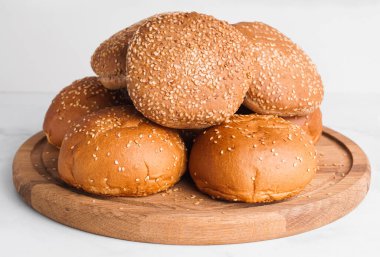 Fresh buns with sesame seeds on white marble table