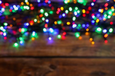 Glowing festive lights on wooden table, top view with space for text. Bokeh effect