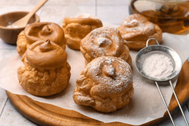 Delicious profiteroles with powdered sugar on white table, closeup