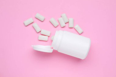Jar with chewing gums on pink background, flat lay