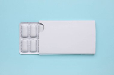Blister with chewing gums on light blue background, top view