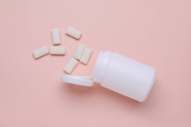 Jar with chewing gums on light pink background, flat lay