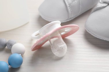 Baby pacifier on white wooden table, closeup