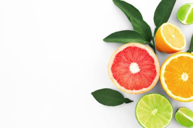 Different citrus fruits and leaves on white background, top view