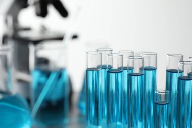 Test tubes with light blue liquid in laboratory, closeup. Space for text