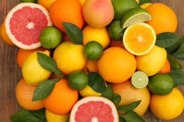 Tahta masada yeşil yapraklı farklı narenciye meyveleri vardı.