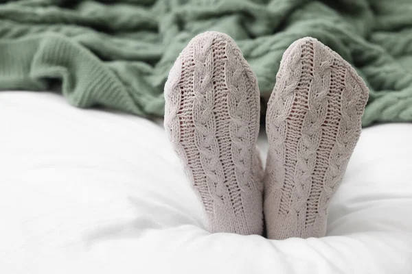 Woman in warm socks lying on bed, closeup. Space for text