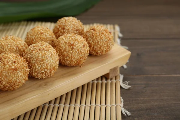 Many delicious sesame balls on wooden table, closeup. Space for text