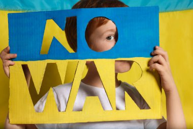 Boy holding poster No War against Ukrainian flag