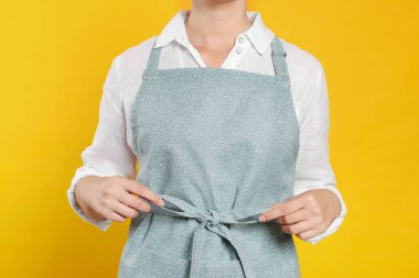 Woman in clean apron with pattern on orange background, closeup