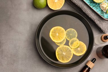 Yağ ve limon içeren düz bileşim gri masada, metin için boşluk. Aromaterapi tedavisi