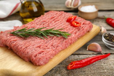 Raw fresh minced meat and ingredients on wooden table, closeup