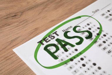 Answer sheet with word Pass on wooden table, closeup. Student passing exam