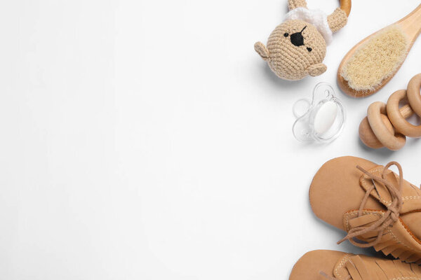Flat lay composition with pacifier and other baby stuff on white background. Space for text