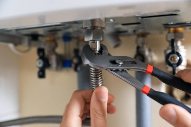 Man repairing gas boiler with waterpump plier, closeup