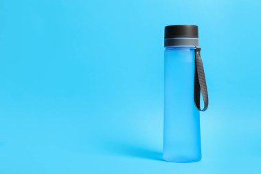 Stylish bottle on light blue background, space for text