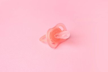 One new baby pacifier on pink background