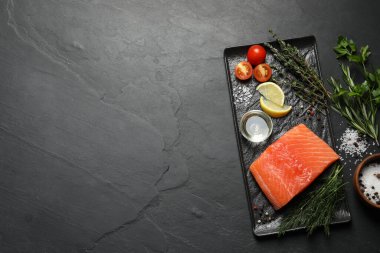 Fresh raw salmon and ingredients for marinade on black table, flat lay. Space for tex