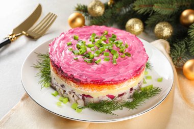 Herring under fur coat salad and Christmas decor on light grey table. Traditional Russian dish