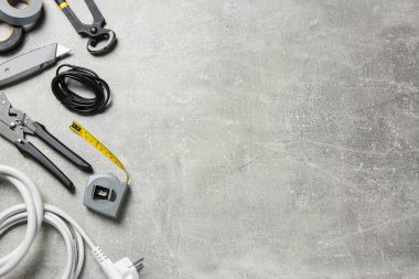 New wires and electrician's tools on grey table, flat lay. Space for text