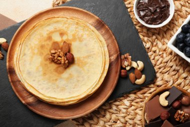 Delicious crepes with nuts and chocolate on table, flat lay
