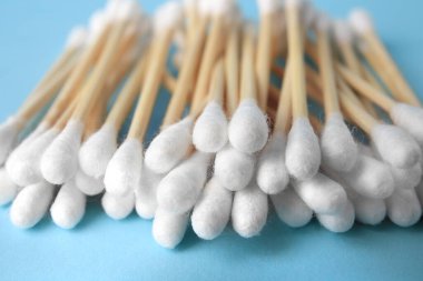Heap of clean cotton buds on light blue background, closeup