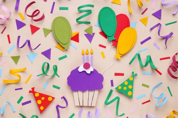Birthday party. Paper cupcake and confetti on beige background, flat lay