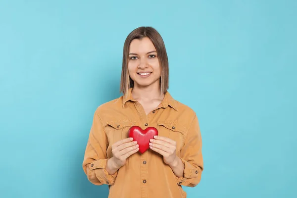 Young Woman Holding Red Heart Turquoise Background Volunteer Concept — Stockfoto