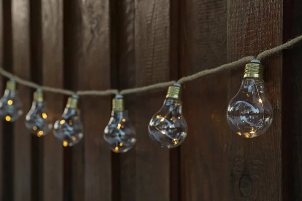 Garland of lamp bulbs hanging on wooden wall. String lights