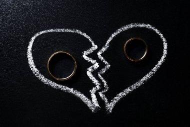 Divorce concept. Wedding rings and broken heart drawn on blackboard, flat lay clipart