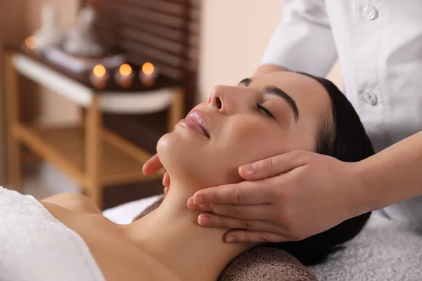 Young woman enjoying professional massage in spa salon, closeup
