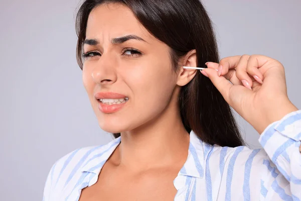 Young Woman Cleaning Ear Cotton Swab Light Grey Background Closeup — Stok fotoğraf