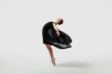 Young ballerina practicing dance moves on white background