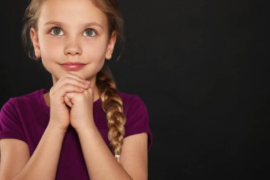 Elleri sımsıkı bağlı siyah arkaplanda dua eden kız, metin için boşluk