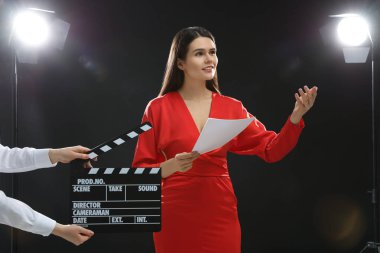 Emotional actress performing role while second assistant camera holding clapperboard on stage. Film industry