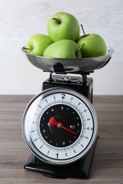 Kitchen scale with green apples on wooden table
