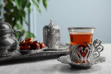Tea and date fruits served in vintage tea set on grey table, space for text