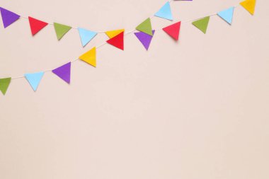 Colorful bunting flags on beige background, flat lay. Space for text